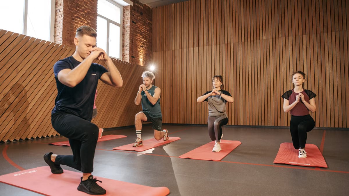 Adults practicing exercises on yoga mats in a contemporary studio setting.